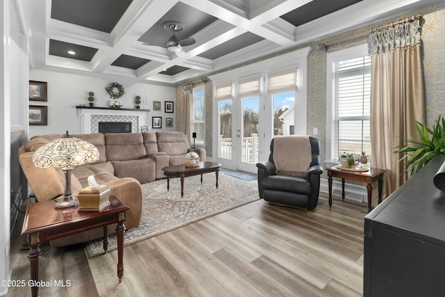 living area featuring beam ceiling, light wood-style flooring, a ceiling fan, and a wealth of natural light