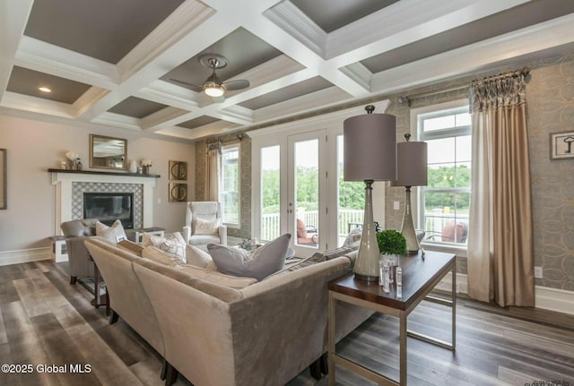 living room featuring coffered ceiling, dark wood-style flooring, ornamental molding, a tile fireplace, and beamed ceiling