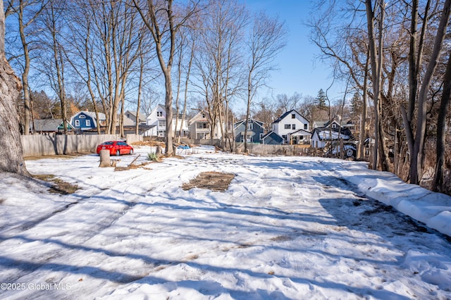 yard layered in snow featuring fence and a residential view