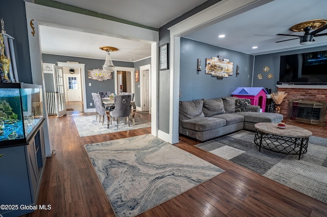 living room featuring a notable chandelier, wood-type flooring, a fireplace, and baseboards