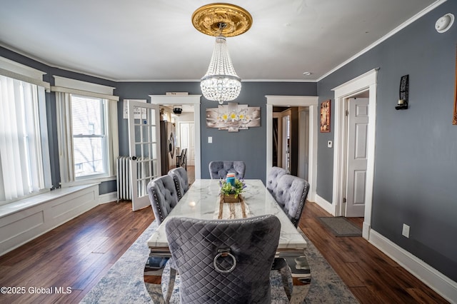 dining area featuring dark wood-style floors, crown molding, baseboards, and an inviting chandelier