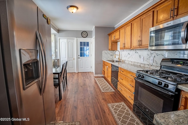 kitchen featuring brown cabinets, dark wood finished floors, decorative backsplash, a sink, and black appliances