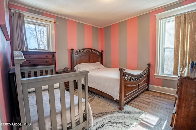 bedroom with wallpapered walls, baseboards, ornamental molding, and wood finished floors