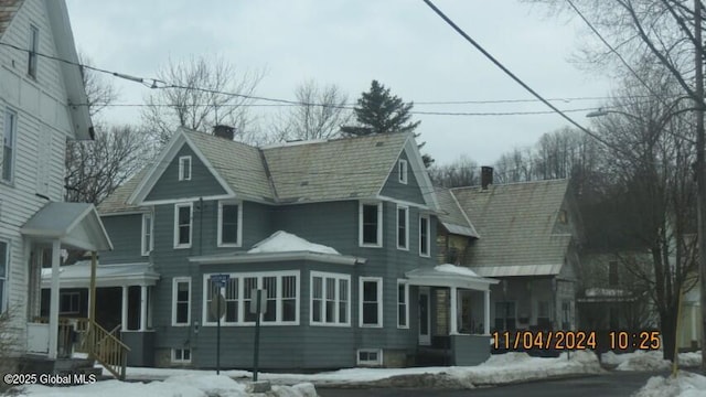 snow covered rear of property with a chimney