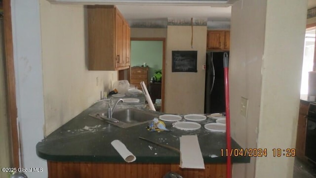 kitchen with brown cabinets, freestanding refrigerator, and a sink