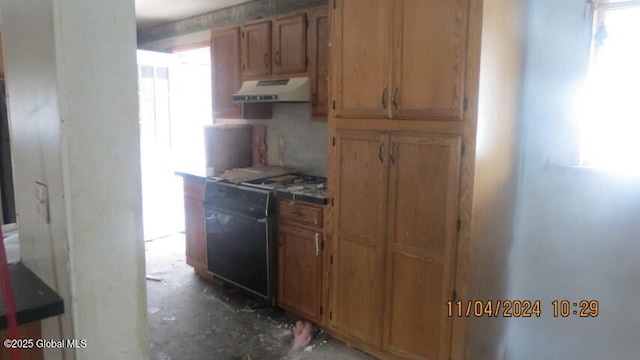 kitchen featuring under cabinet range hood, stove, and brown cabinetry