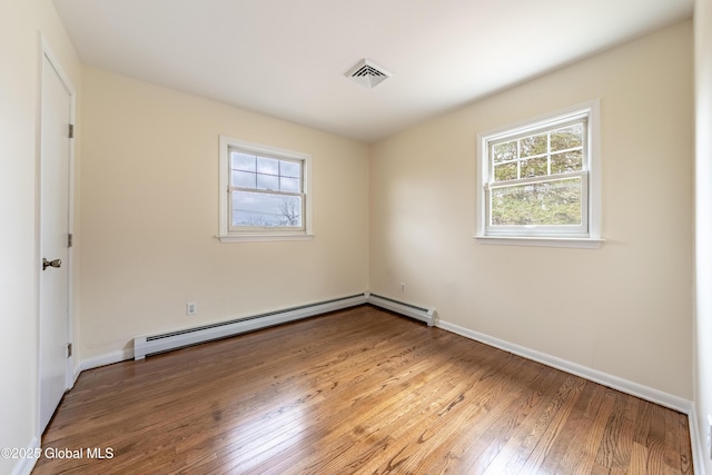 spare room featuring baseboards, a baseboard radiator, visible vents, and light wood-style floors