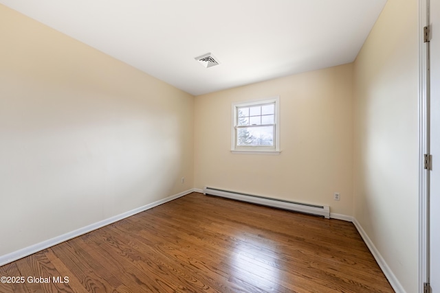 spare room featuring visible vents, baseboards, baseboard heating, and wood finished floors