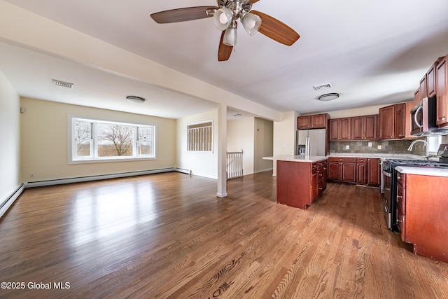 kitchen featuring visible vents, dark wood-style floors, stainless steel appliances, light countertops, and a baseboard heating unit