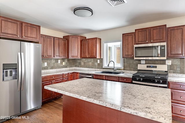 kitchen with visible vents, appliances with stainless steel finishes, wood finished floors, light countertops, and a sink