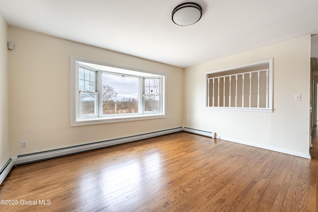 spare room with baseboards, baseboard heating, and wood finished floors