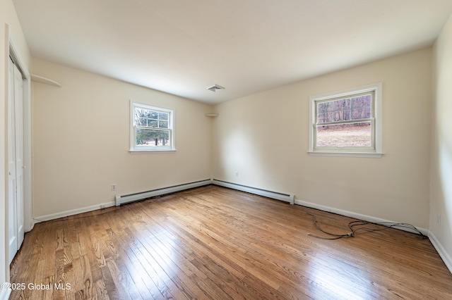 unfurnished bedroom featuring a baseboard radiator, hardwood / wood-style flooring, visible vents, baseboards, and baseboard heating