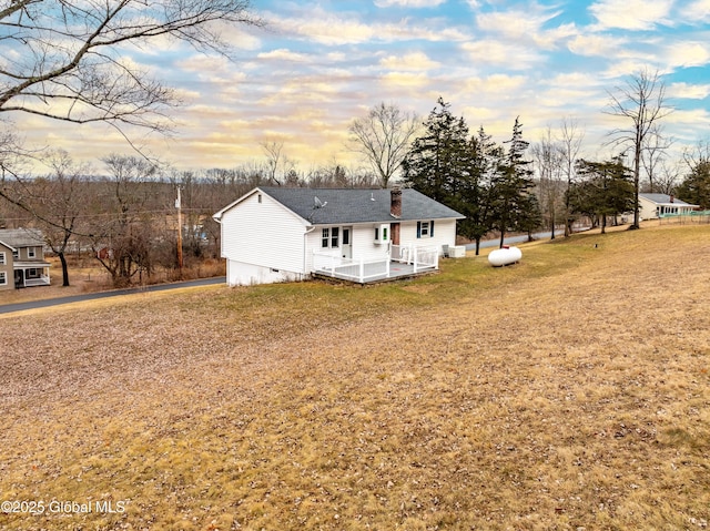 view of front of home featuring crawl space, a deck, a chimney, and a front lawn