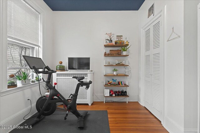 workout area featuring baseboards, visible vents, and wood finished floors