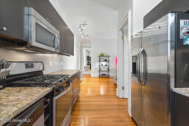 kitchen featuring light wood-style flooring, appliances with stainless steel finishes, decorative backsplash, light stone countertops, and modern cabinets