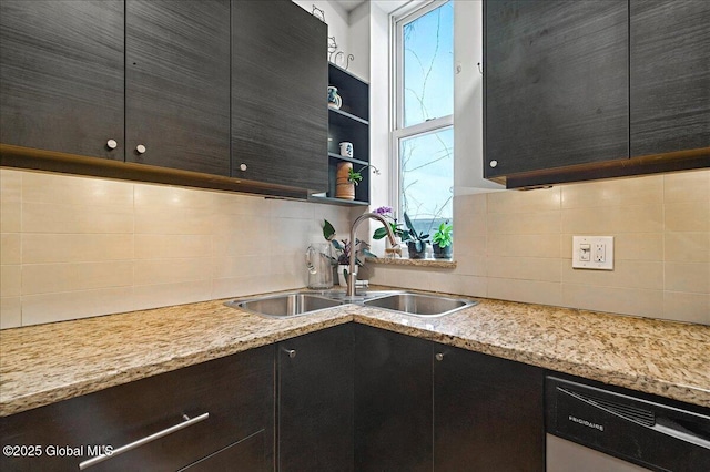 kitchen with dishwashing machine, light stone counters, a sink, decorative backsplash, and open shelves