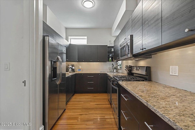 kitchen with open shelves, stainless steel appliances, tasteful backsplash, light wood-style flooring, and a sink