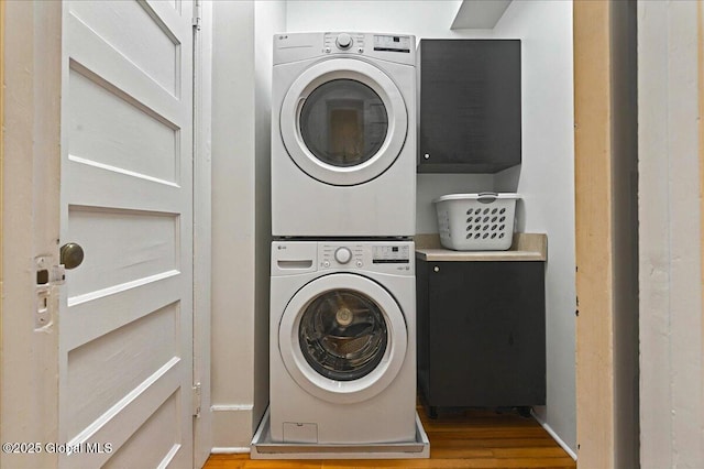 washroom featuring laundry area, wood finished floors, and stacked washer / drying machine