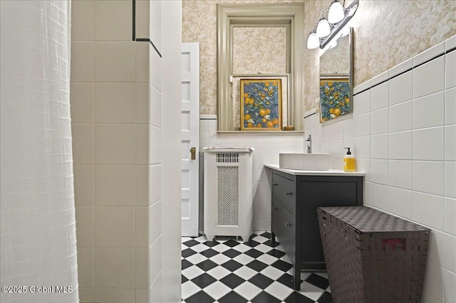 full bath with wallpapered walls, radiator heating unit, tile patterned floors, vanity, and tile walls