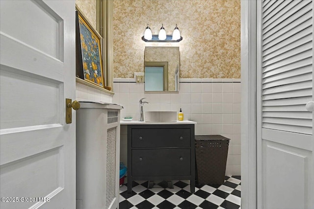 bathroom featuring wallpapered walls, wainscoting, tile walls, and tile patterned floors