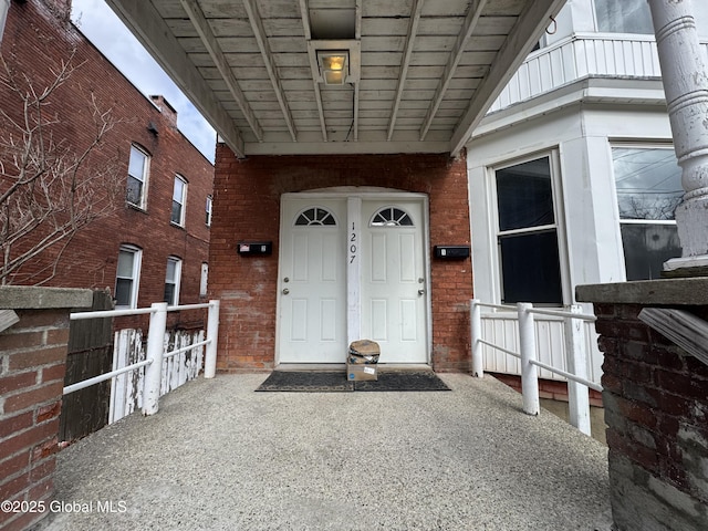 property entrance featuring covered porch and brick siding