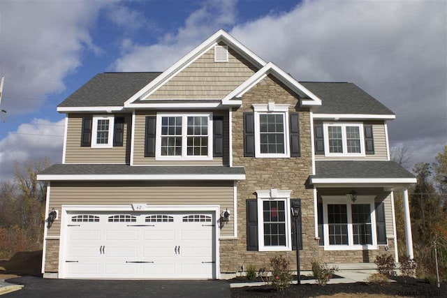 craftsman-style house with stone siding, aphalt driveway, an attached garage, and a shingled roof