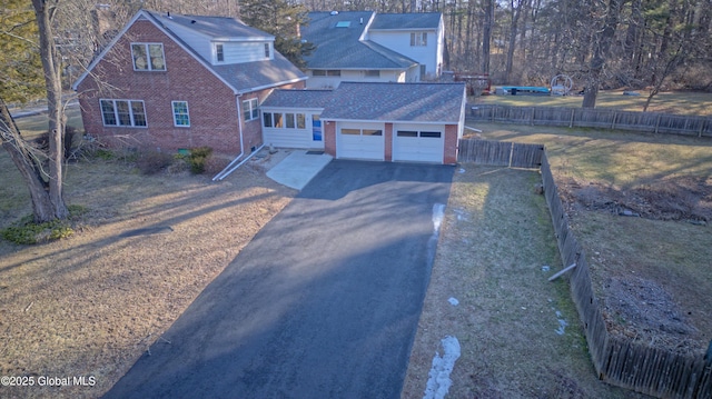 view of front of property with fence, driveway, roof with shingles, a garage, and brick siding