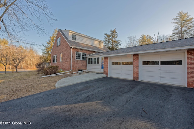 view of front facade with aphalt driveway, a garage, and brick siding