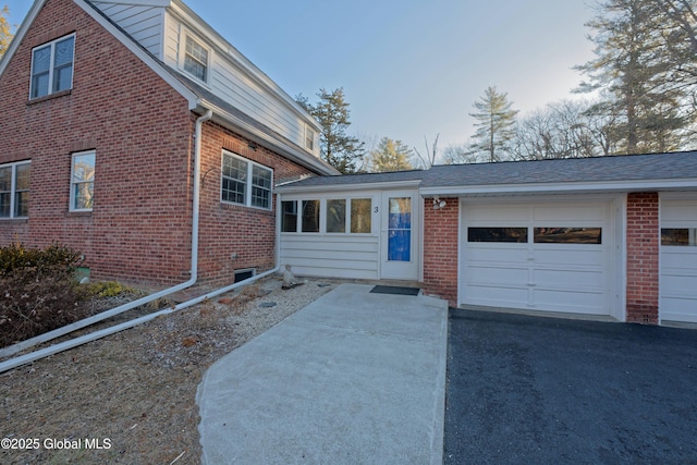 view of front of home with brick siding, driveway, and a garage