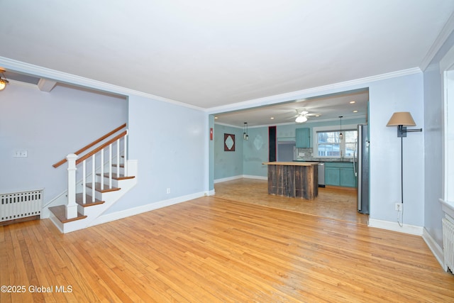 unfurnished living room with radiator heating unit, stairway, crown molding, light wood finished floors, and baseboards