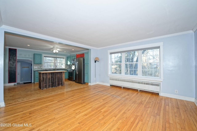 unfurnished living room featuring a sink, radiator, crown molding, light wood finished floors, and baseboards