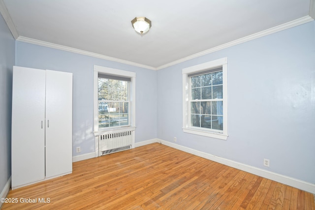 unfurnished bedroom featuring crown molding, radiator heating unit, baseboards, and light wood finished floors