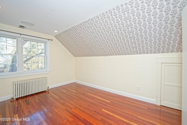 additional living space with visible vents, radiator, baseboards, and hardwood / wood-style flooring