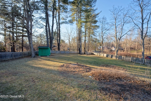 view of yard with an outbuilding, a storage unit, and a fenced backyard