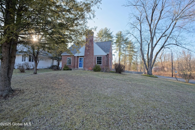 view of front of property with brick siding, a chimney, and a front yard