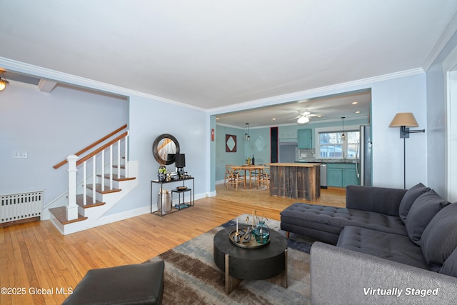 living area featuring crown molding, baseboards, stairs, radiator heating unit, and light wood-style flooring