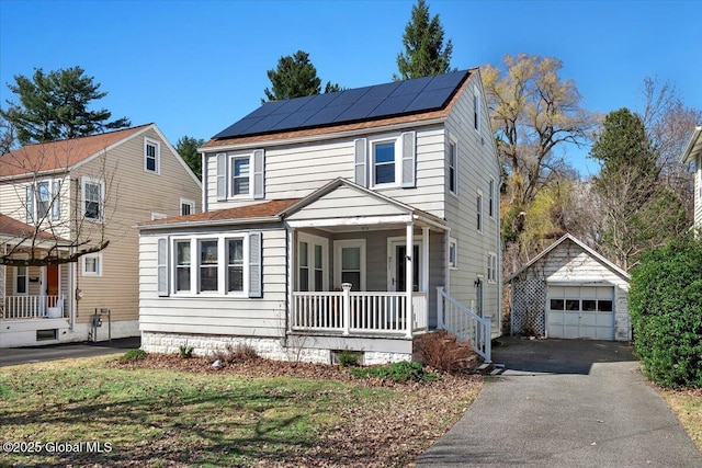 view of front of home featuring aphalt driveway, a porch, roof mounted solar panels, a garage, and an outbuilding