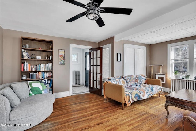 living area featuring light wood-style flooring, radiator, baseboards, and ceiling fan