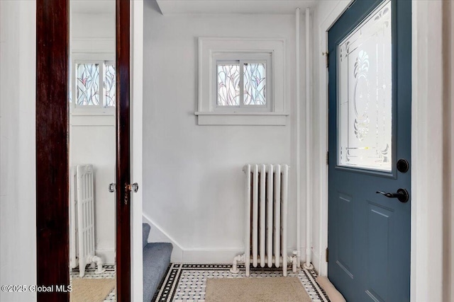 doorway featuring stairs, radiator, and baseboards