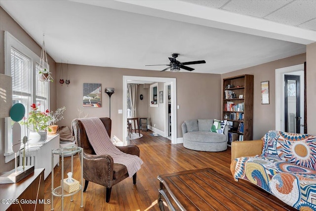 living area with wood finished floors, baseboards, and ceiling fan