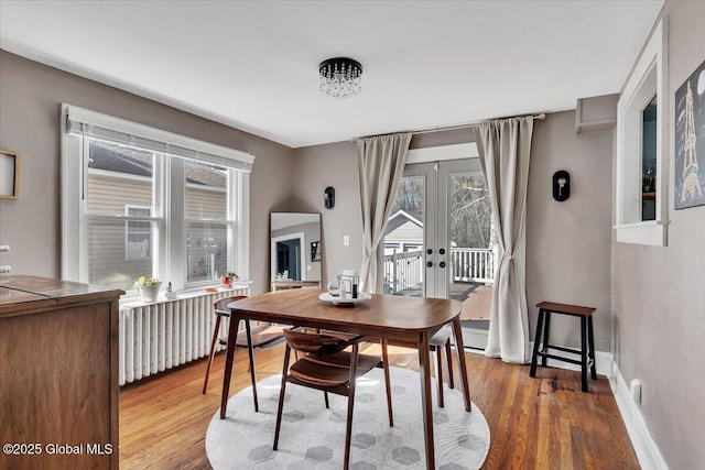 dining area with french doors, baseboards, radiator, and wood finished floors