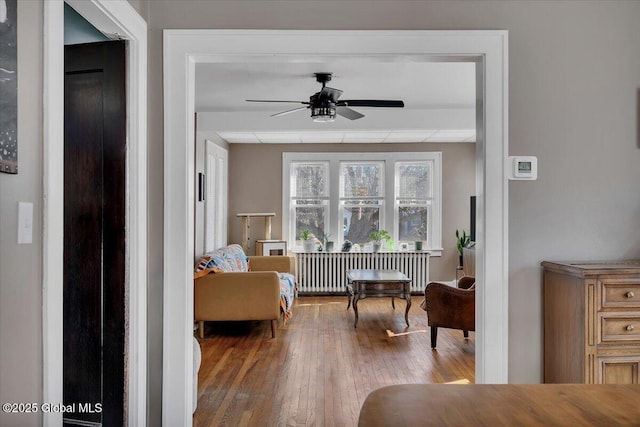 living area with radiator, ceiling fan, and wood finished floors