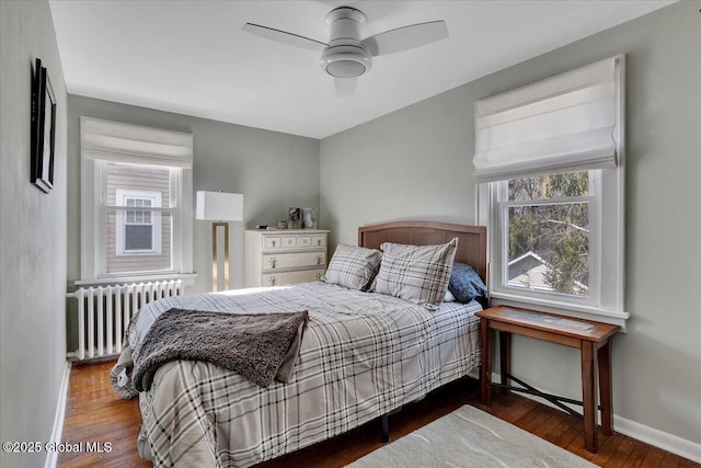 bedroom with baseboards, multiple windows, radiator, and wood finished floors