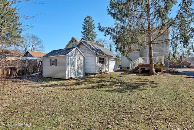 rear view of property featuring an outdoor structure, a lawn, fence, and a shed