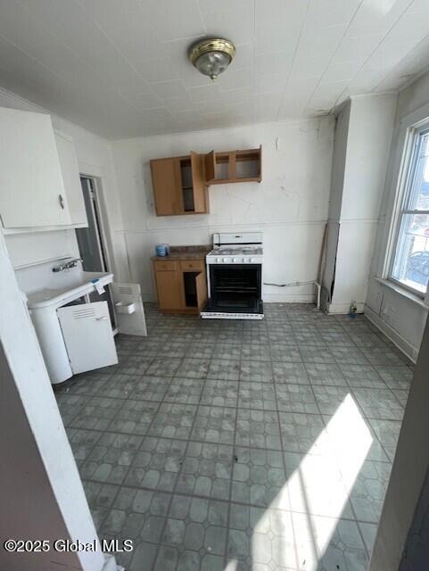 kitchen featuring brown cabinetry, gas range, dark floors, and open shelves