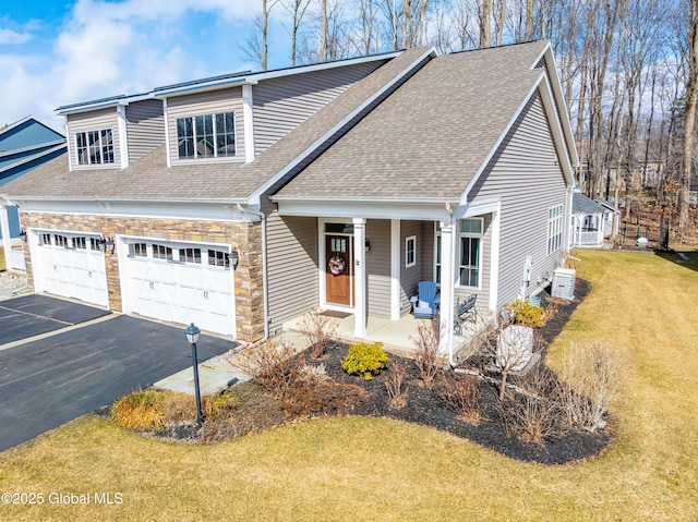 view of front of home featuring a front lawn, aphalt driveway, a porch, roof with shingles, and stone siding