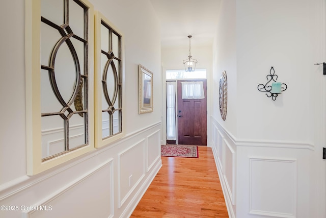 entryway with a decorative wall, light wood-style floors, and wainscoting