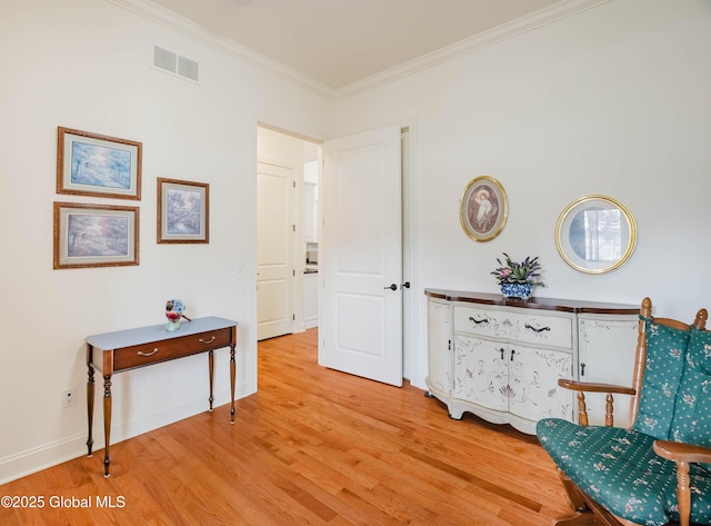 sitting room with visible vents, baseboards, light wood-style flooring, and crown molding