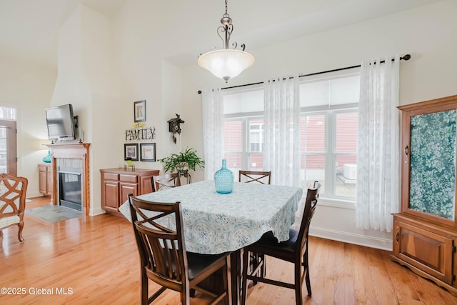 dining space featuring light wood-type flooring, baseboards, and a fireplace