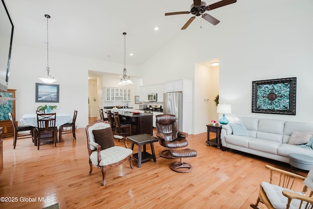 living area featuring recessed lighting, ceiling fan with notable chandelier, high vaulted ceiling, and light wood-style floors